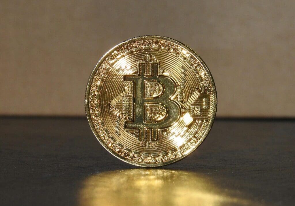 Gold Bitcoin coin on reflective surface