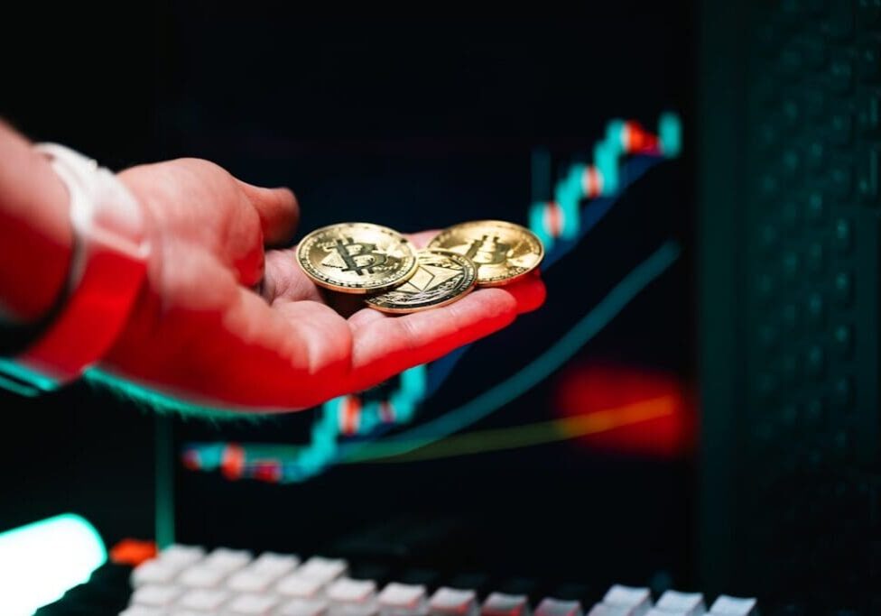 Hand holding cryptocurrency coins, market chart background